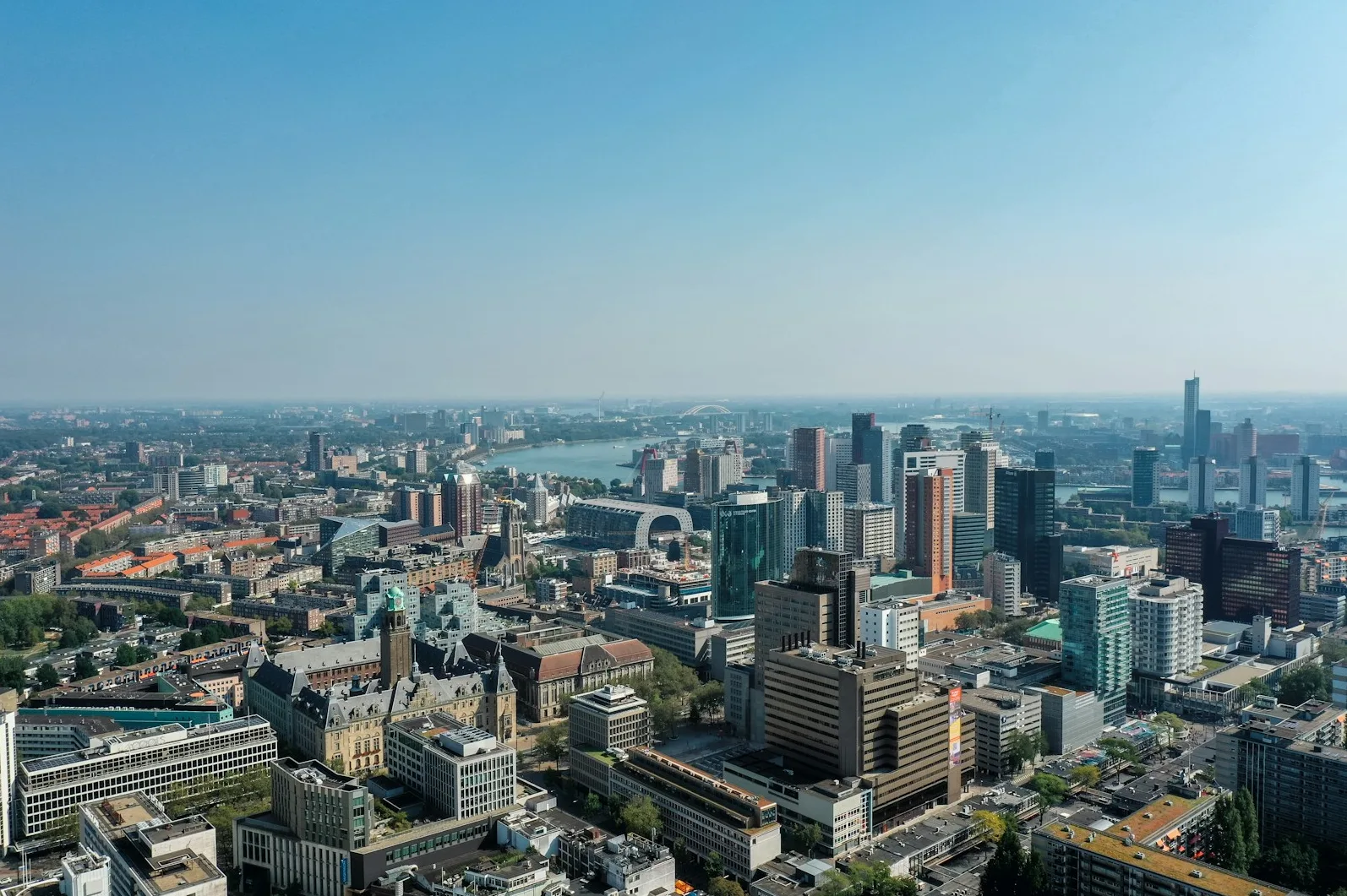 Panoramski pogled iz zraka na moderni grad Rotterdam s visokim zgradama, rijekom i mostom u daljini.