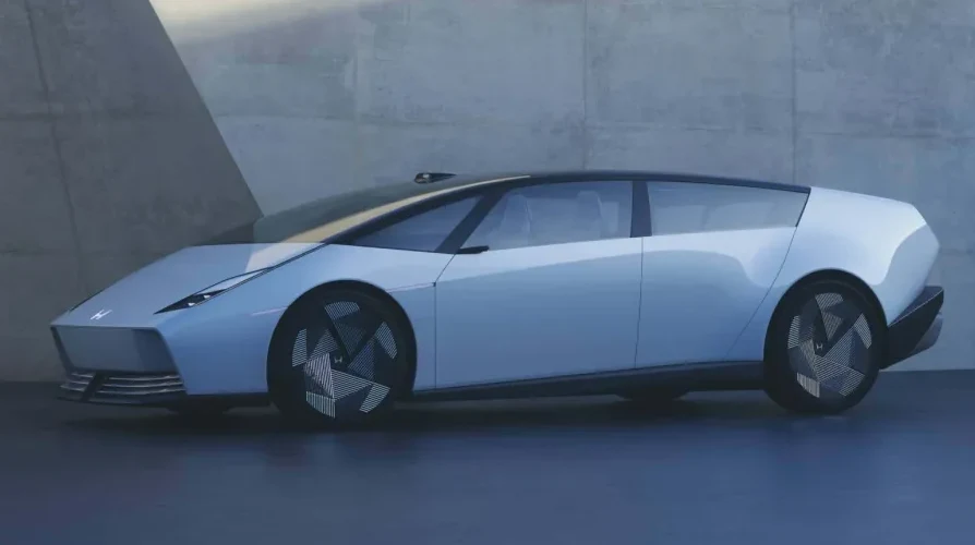 Futuristički koncept automobil u svjetloplavoj boji sa oštrim linijama, tamnim krovom i jedinstvenim dizajnom točkova, prikazan sa strane ispred betonskog zida.