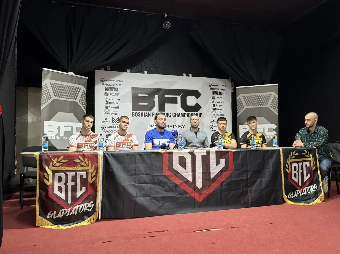 Šest muškaraca sjedi za stolom ispred zastora na konferenciji za medije. Ispred stola nalaze se transparenti sa natpisom "BFC Gladiators". Na stolu su boce vode i mikrofoni.