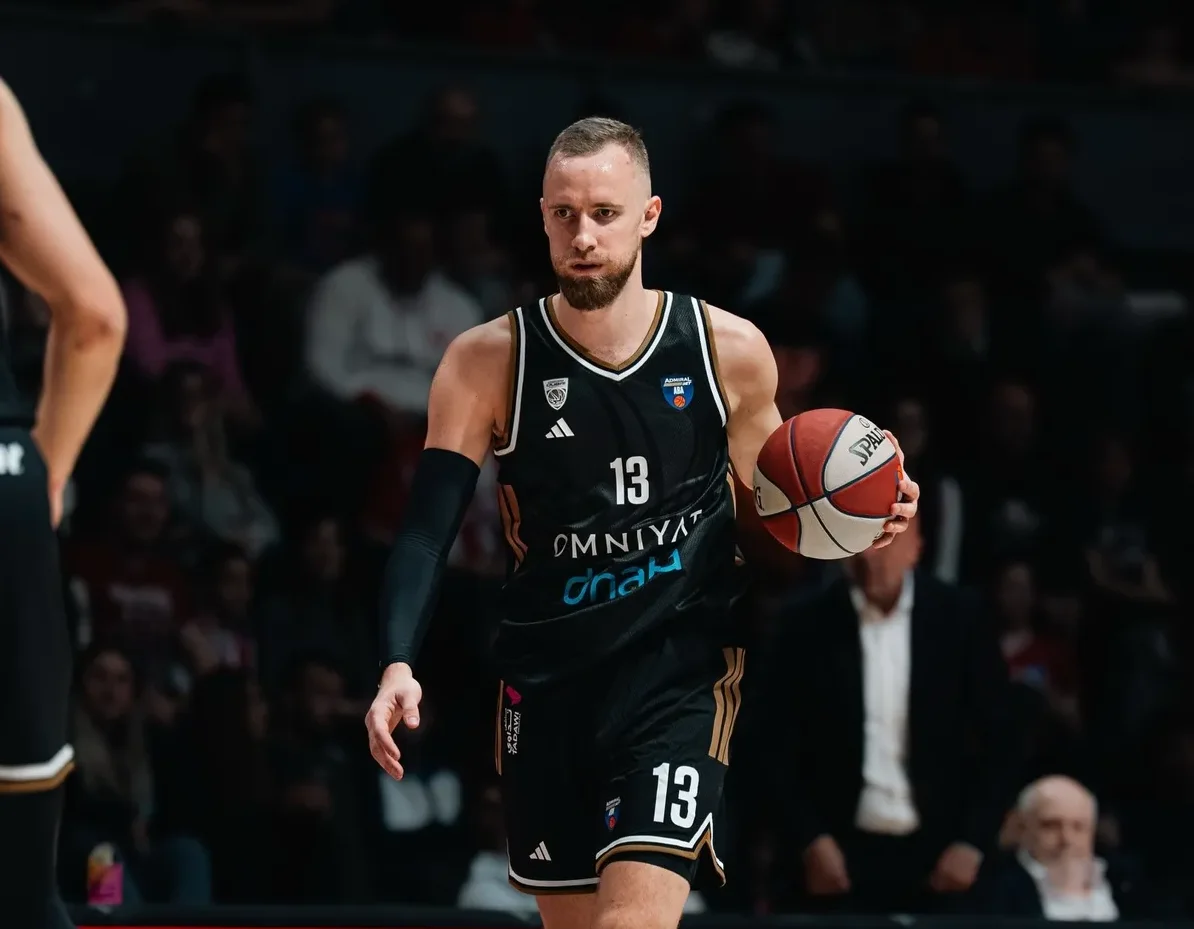 Košarkaš u crnom dresu sa brojem 13 i bradom, drži košarkašku loptu.