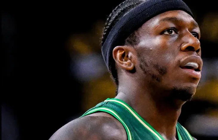 Portret tamnoputog košarkaša koji nosi zeleni dres i crnu traku oko glave, fokusiran prema gore.