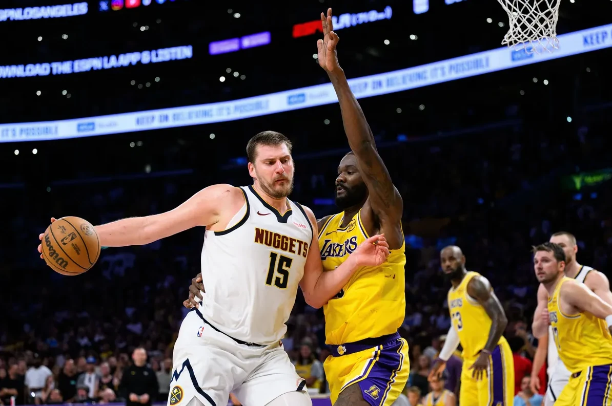 Nikola Jokić iz Denver Nuggetsa sa brojem 15 sa loptom u ruci, čuva ga igrač Los Angeles Lakersa.