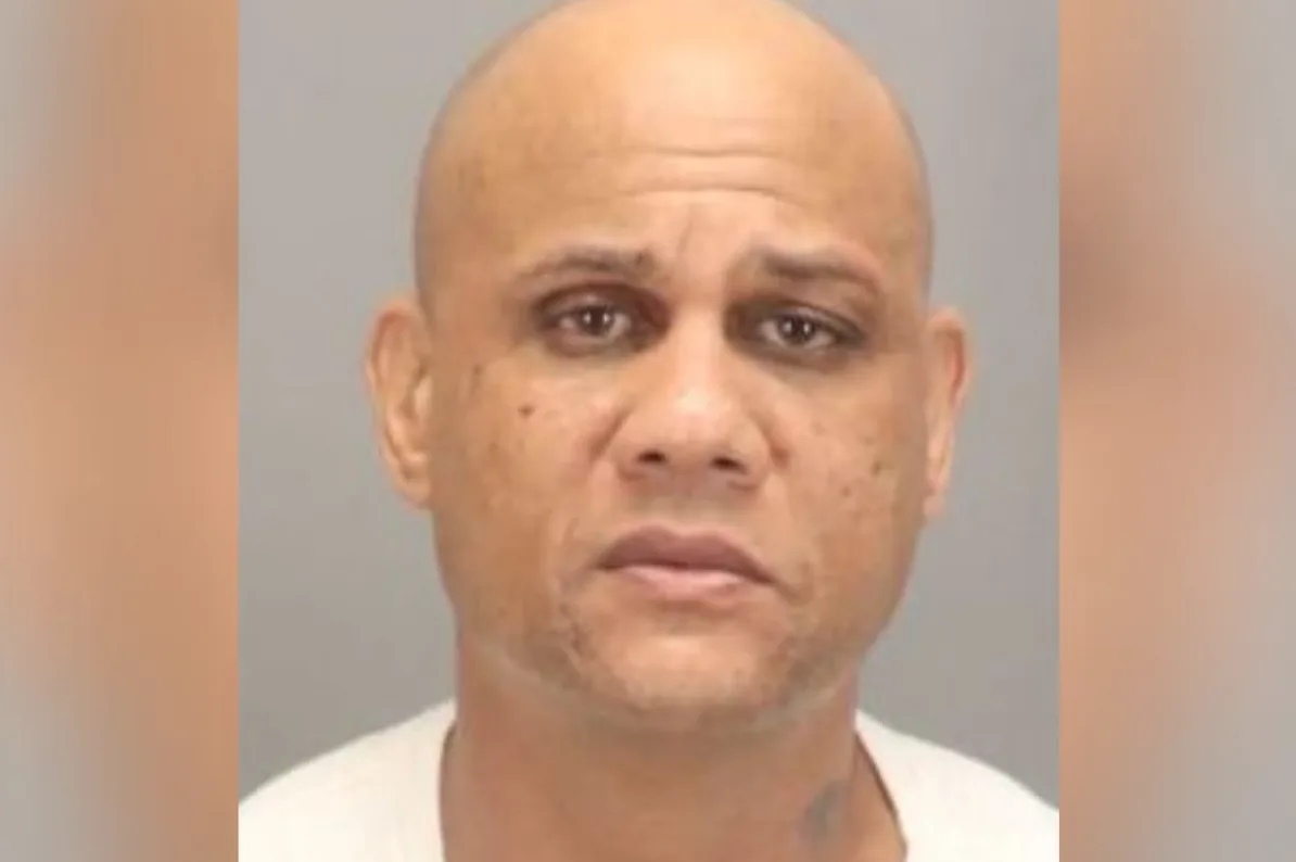 Portret ćelavog muškarca sa tamnom kožom i smeđim očima.