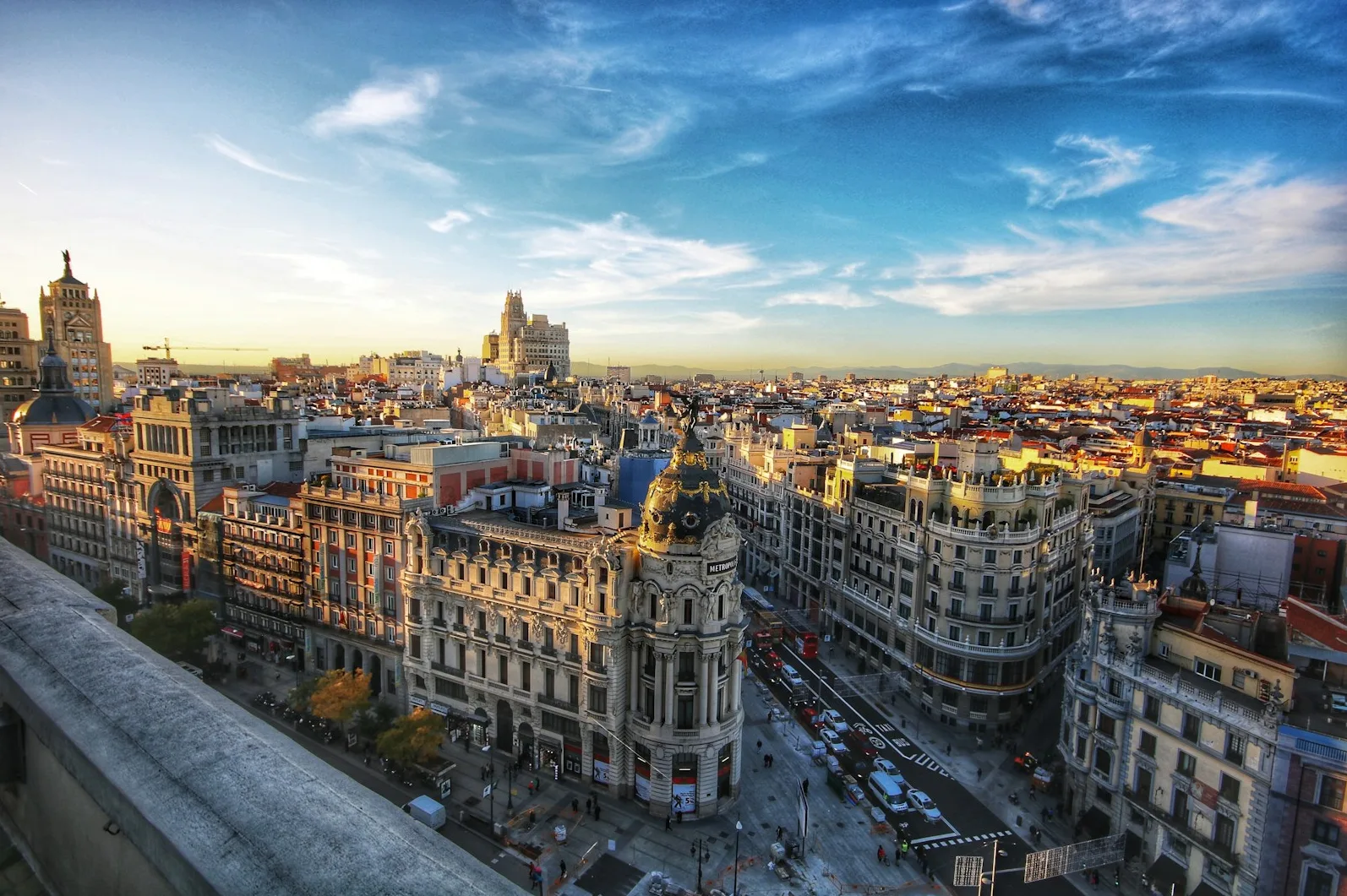 Panoramski pogled na Madrid pri zalasku sunca s poznatom zgradom Metropolis u prvom planu.