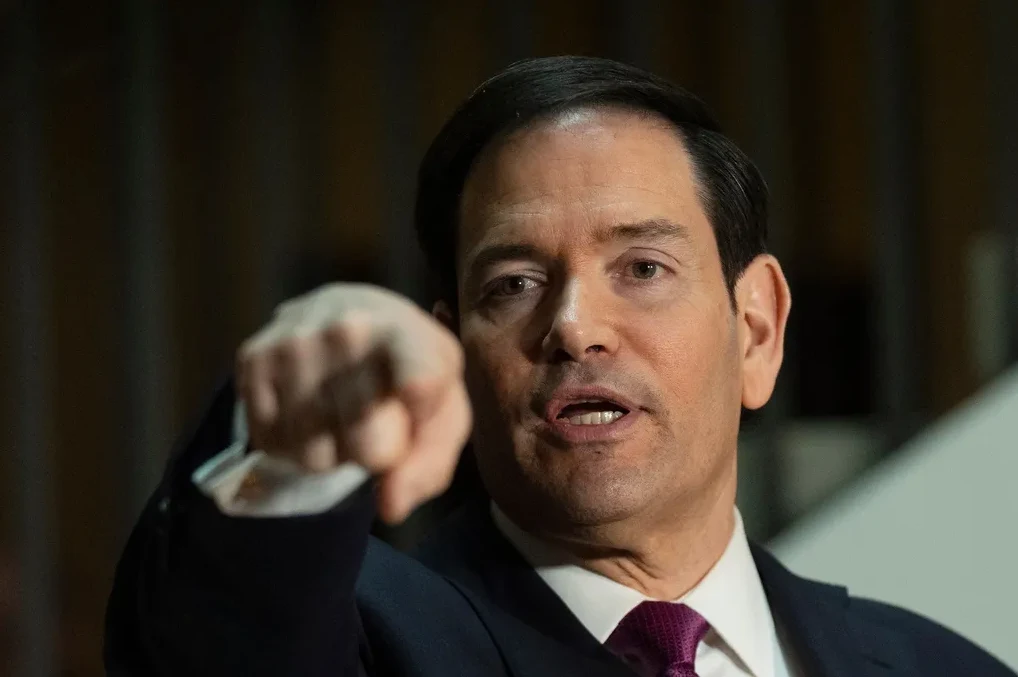 Senator Marco Rubio u tamnom odijelu i ljubičastoj kravati usmjeren prstom prema naprijed.