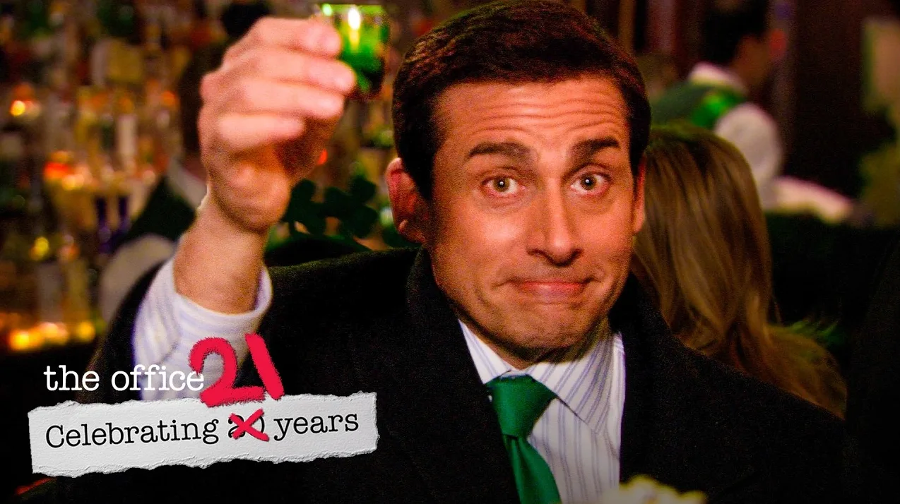 Michael Scott iz serije The Office diže čašicu zelenog pića u zrak, slaveći 21. godišnjicu serije.