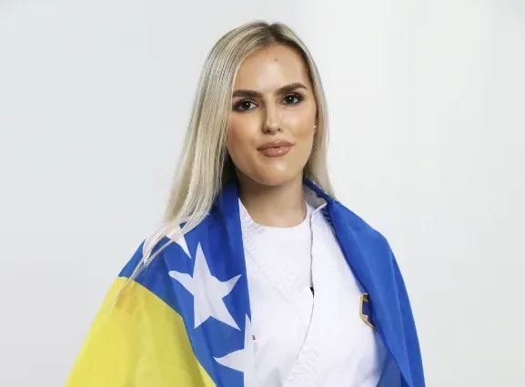 Mlada djevojka u bijelom kimonu sa zastavom Bosne i Hercegovine preko ramena.