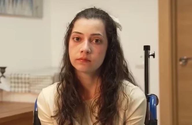 Portret mlade žene sa tamnom kosom, koja sjedi u invalidskim kolicima.