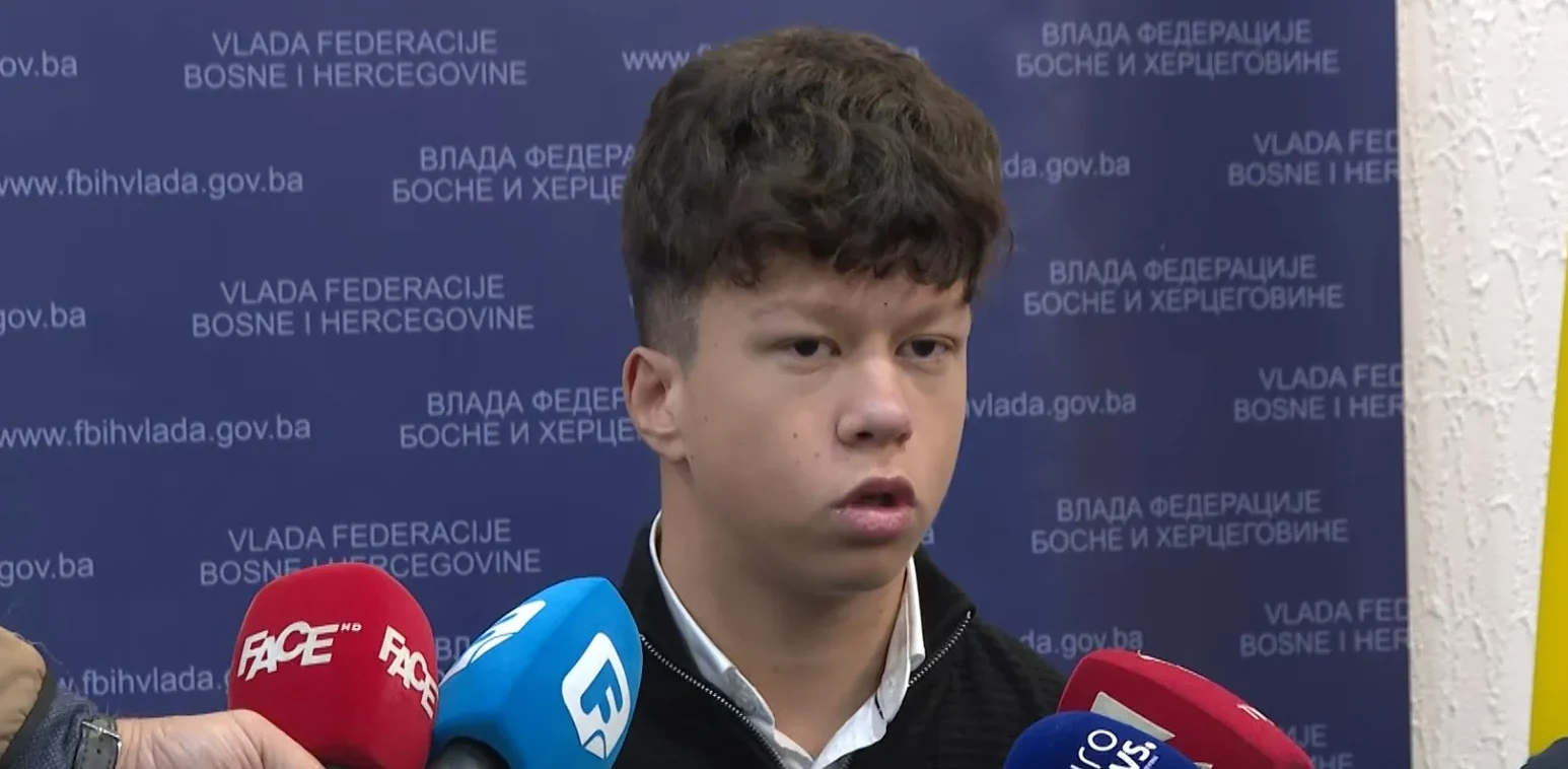 Mladić govori pred novinarima, sa logom Vlade Federacije Bosne i Hercegovine u pozadini i mikrofonima ispred njega.