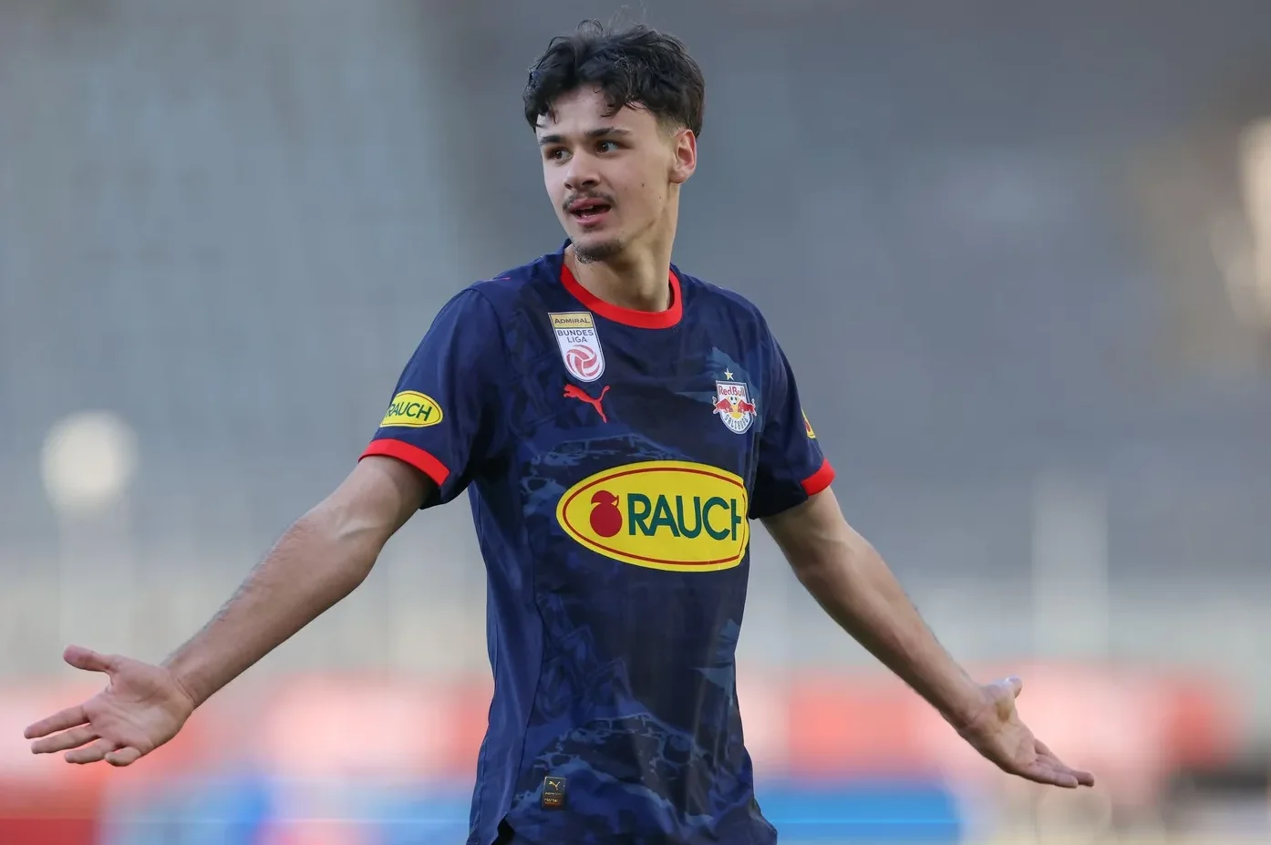 Mladi fudbaler u tamnoplavom dresu Red Bull Salzburga s raširenim rukama.