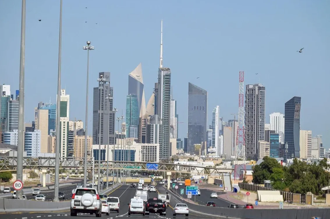 Pogled na savremeni gradski pejzaž sa visokim neboskoderima i užurbanom saobraćajnicom u prvom planu.