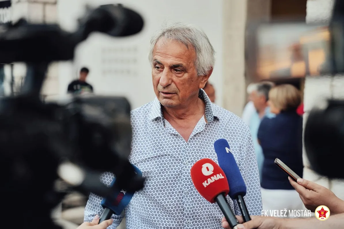 Čovjek sa sijedom kosom, obučen u bijelu košulju sa dezenom zvjezdica, daje izjavu za medije ispred više mikrofona, među kojima su mikrofoni "RTV Mostar" i "Nezavisne novine".