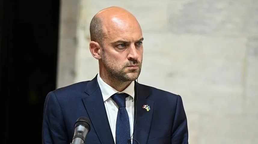 Muškarac u tamnom odijelu i plavoj kravati s iglicom koja prikazuje zastavu Ukrajine.