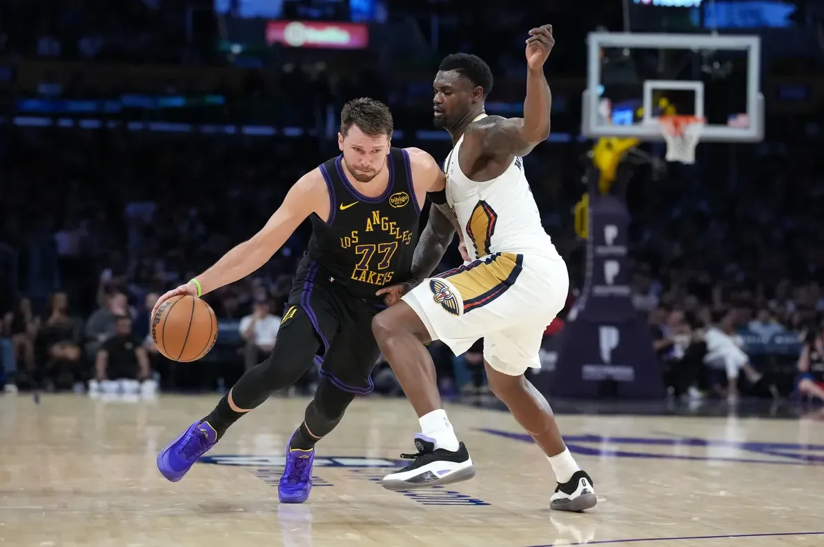 Košarkaš Los Angeles Lakersa sa brojem 77, Luka Dončić, u crnom dresu, vodi loptu dok ga čuva igrač New Orleans Pelicans u bijelom dresu.