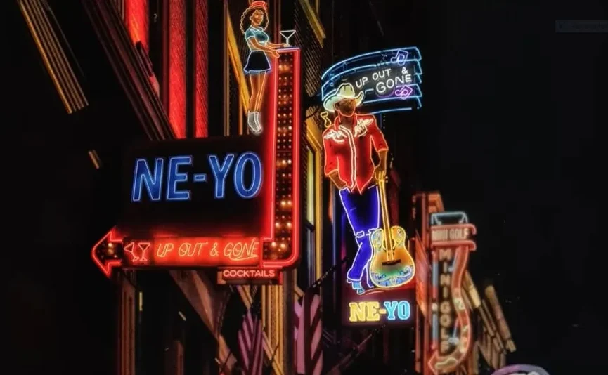 Neonski znakovi iznad ulaznih vrata, na kojima piše "NE-YO" u plavim slovima, te slika kauboja s gitarom i neonski znakovi "UP OUT & GONE" i "COCKTAILS".