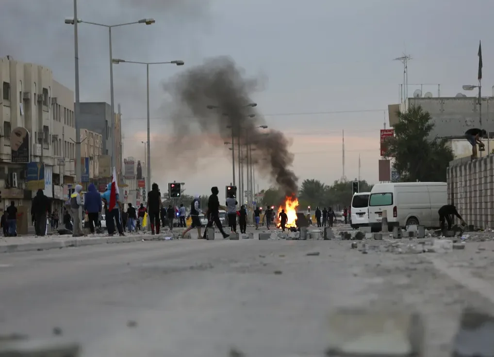 Ljudi na ulici sa zapaljenom vatrom i dimom u pozadini