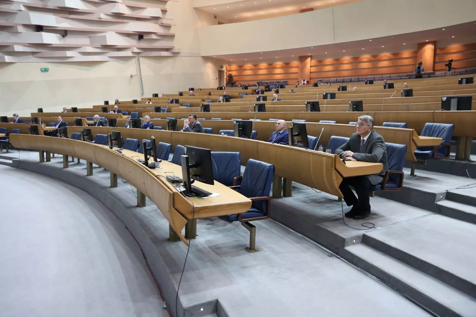 Zgrada parlamenta sa zastupnicima koji sjede u klupama tokom sjednice.