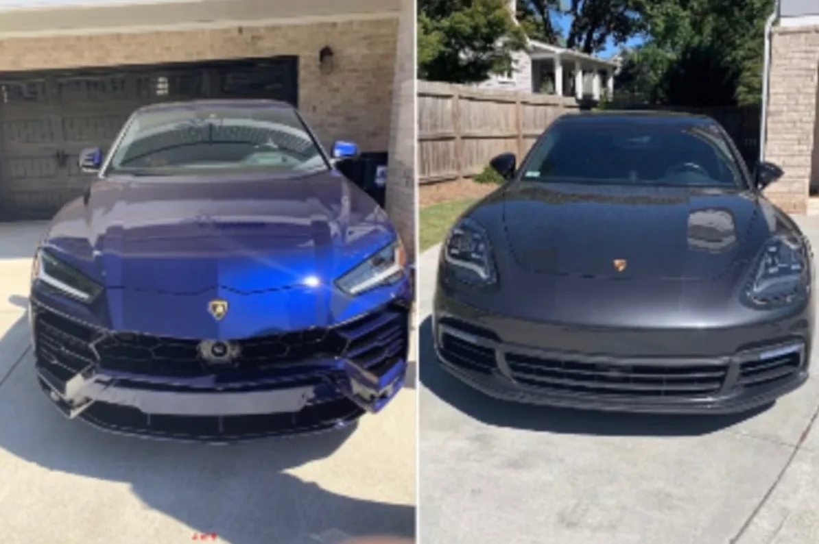 Prednji pogled na plavi Lamborghini i tamni Porsche parkirane ispred garažnih vrata i drvene ograde.