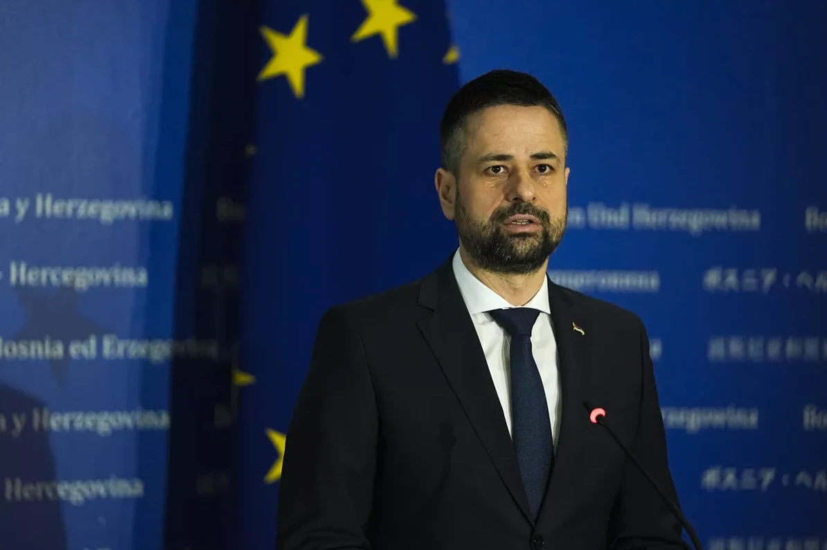 Političar u tamnom odijelu i tamnoplavoj kravati govori ispred zastave Evropske unije i natpisa na kojem se spominje Bosna i Hercegovina.