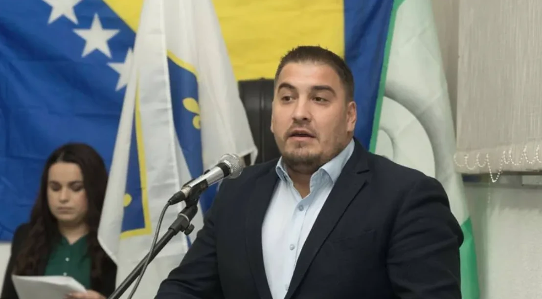 Političar govori ispred mikrofona sa zastavom Bosne i Hercegovine u pozadini.