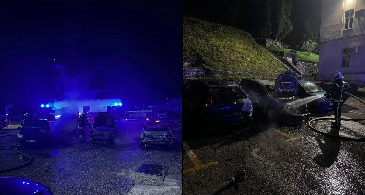 Vatrogasci gase zapaljene automobile noću, jedan vatrogasac prska vodom vozilo sa otvorenim poklopcem motora, dok je drugo vozilo potpuno izgorjelo.