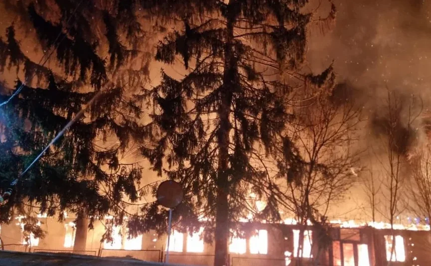 Veliki požar na objektu i u šumi noću, vatrogasci gase vatru.