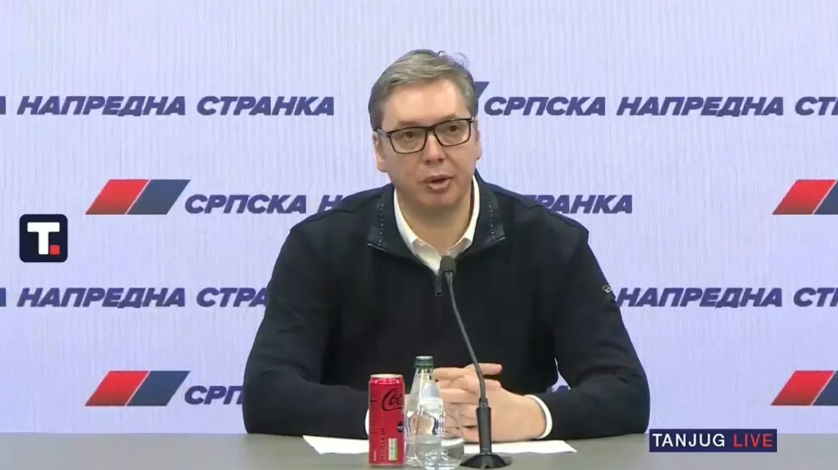 Aleksandar Vučić, predsjednik Srpske napredne stranke, za govornicom sa mikrofonom, ispred banera stranke sa logom.