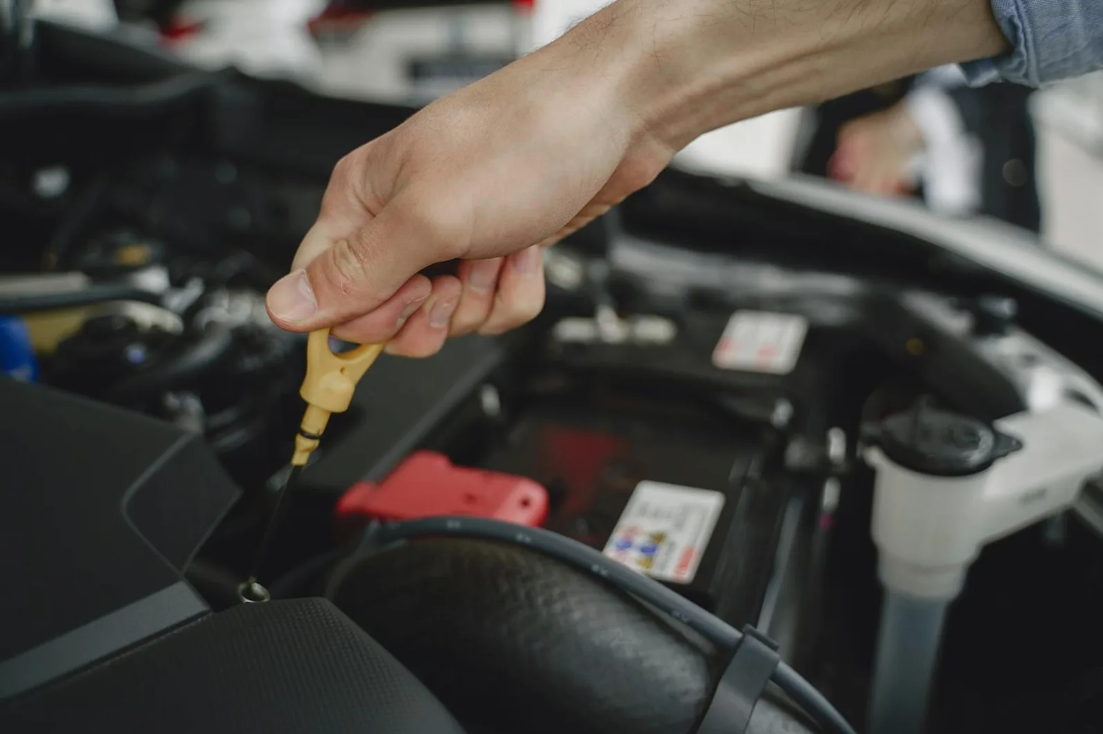 Ruka drži mjernu šipku za provjeru nivoa ulja u motoru automobila