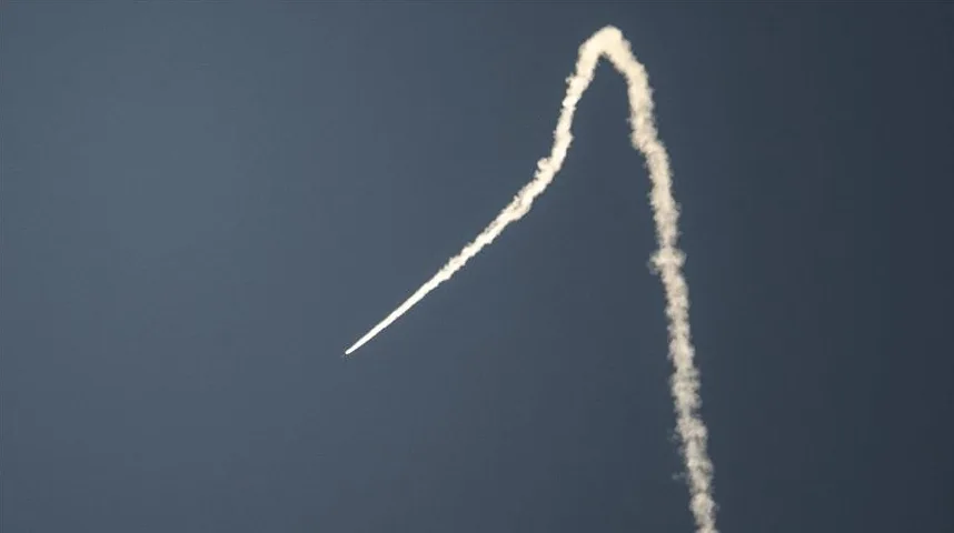 Bijeli trag dima na tamnom nebu, koji podsjeća na putanju rakete koja je u krivini.