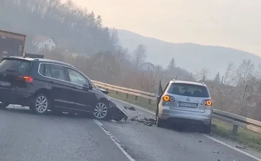 Crni i srebrni automobil su se sudarili na putu, sa vidljivim oštećenjima i krhotinama na kolovozu.