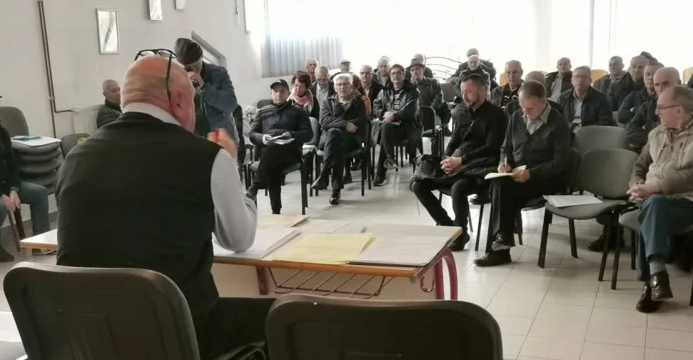 Grupa ljudi sjedi u učionici, sluša predavača