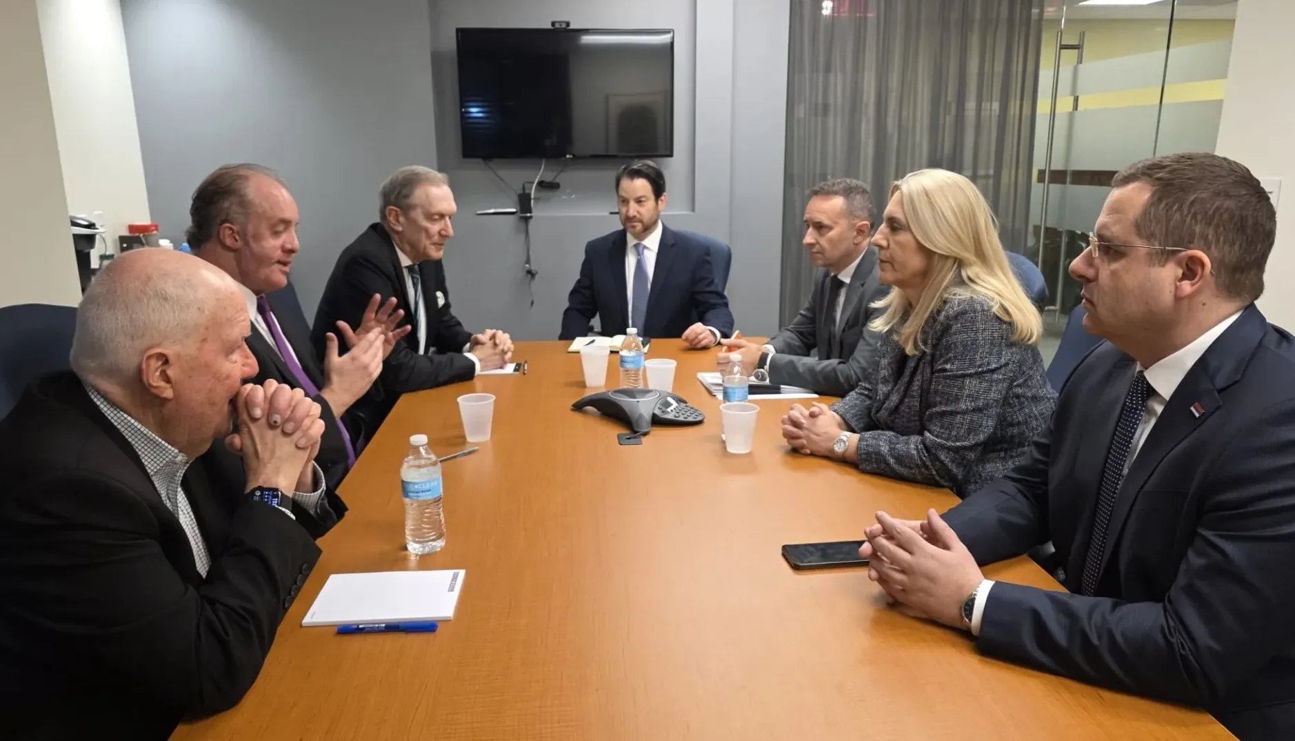 Grupa ljudi na sastanku za drvenim stolom