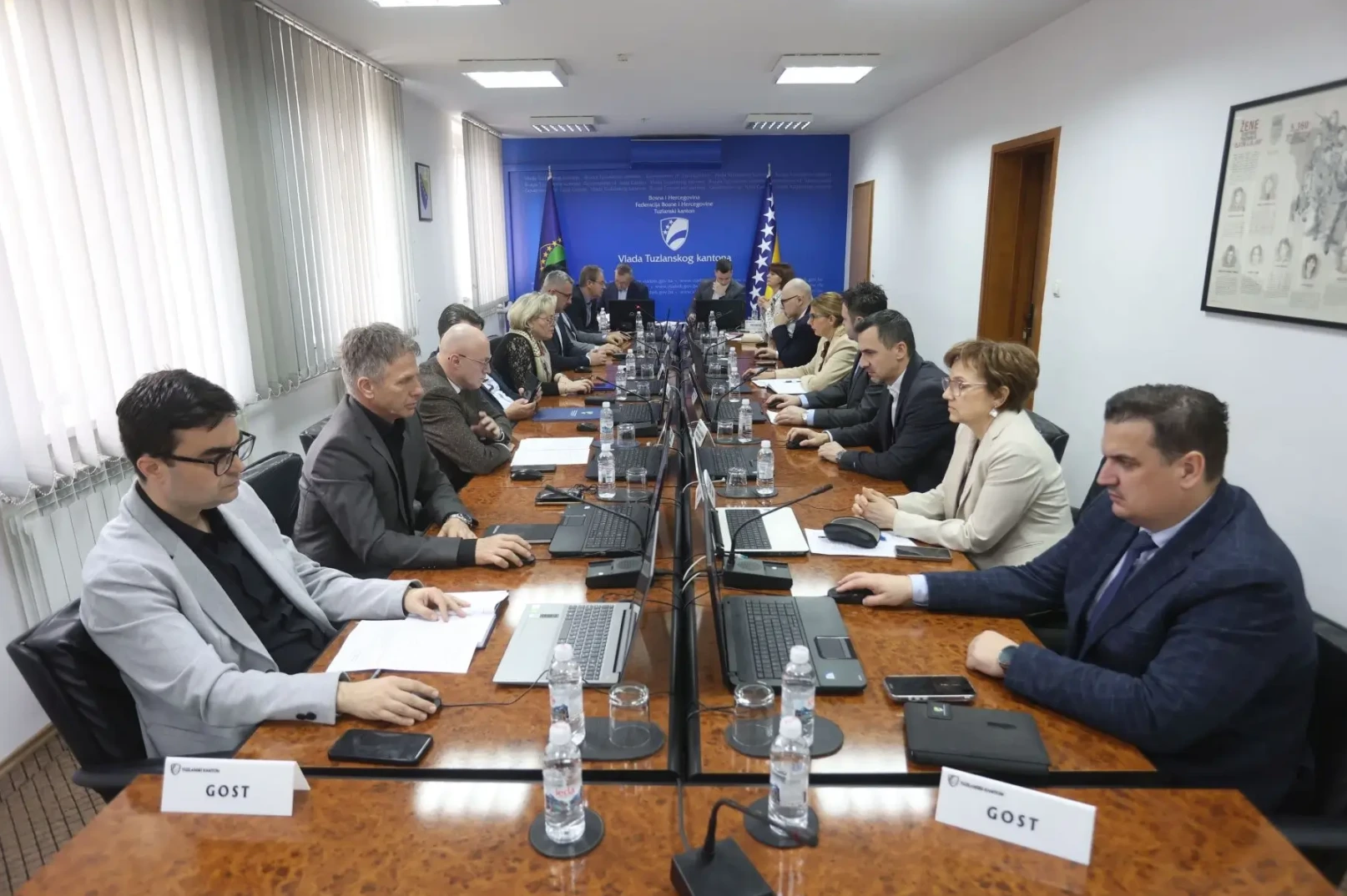 Članovi Vlade Tuzlanskog kantona na sastanku za stolom sa laptopima i dokumentima.