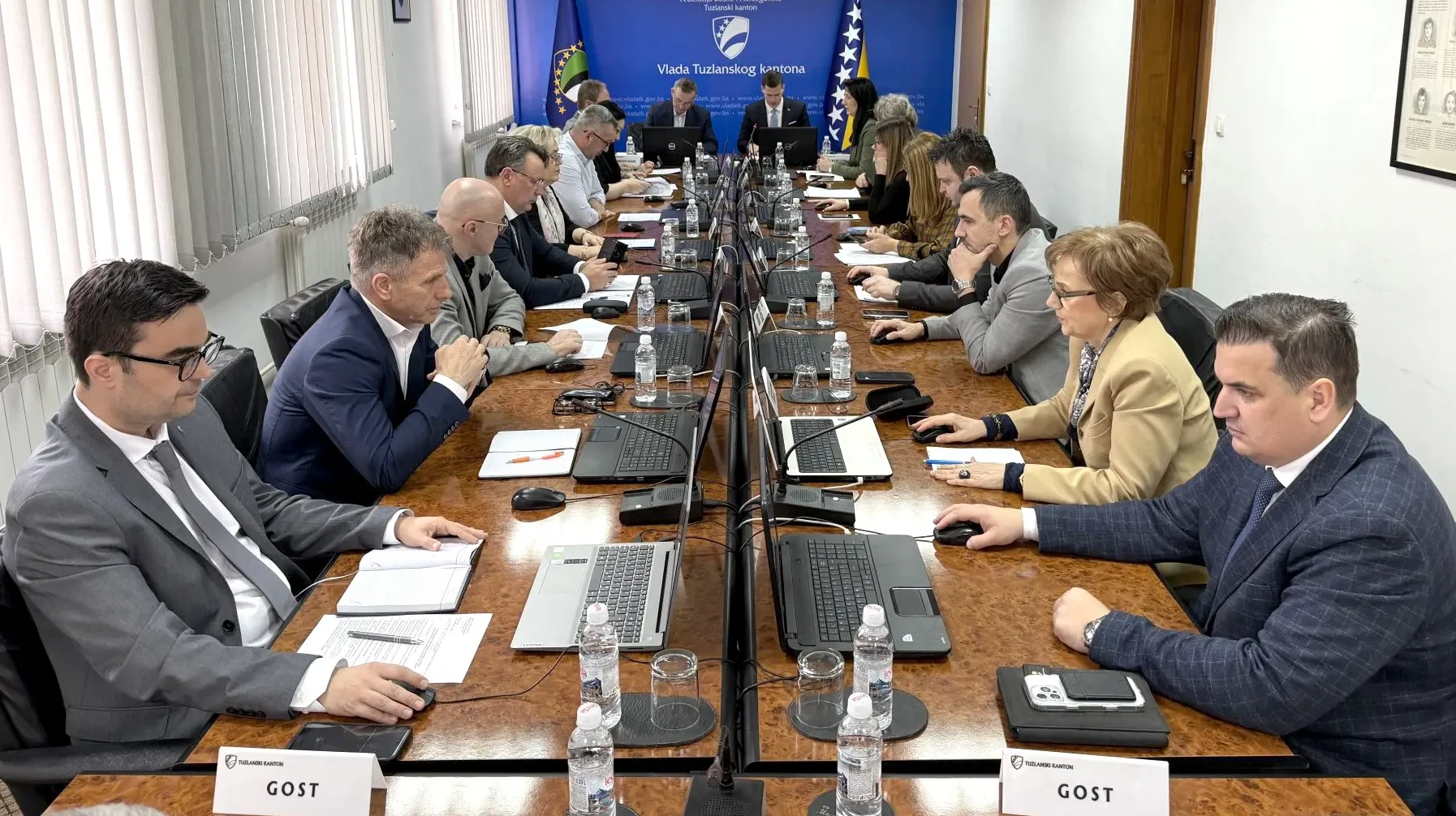 Ljudi sjede za stolom u sali za sastanke i rade na laptopima