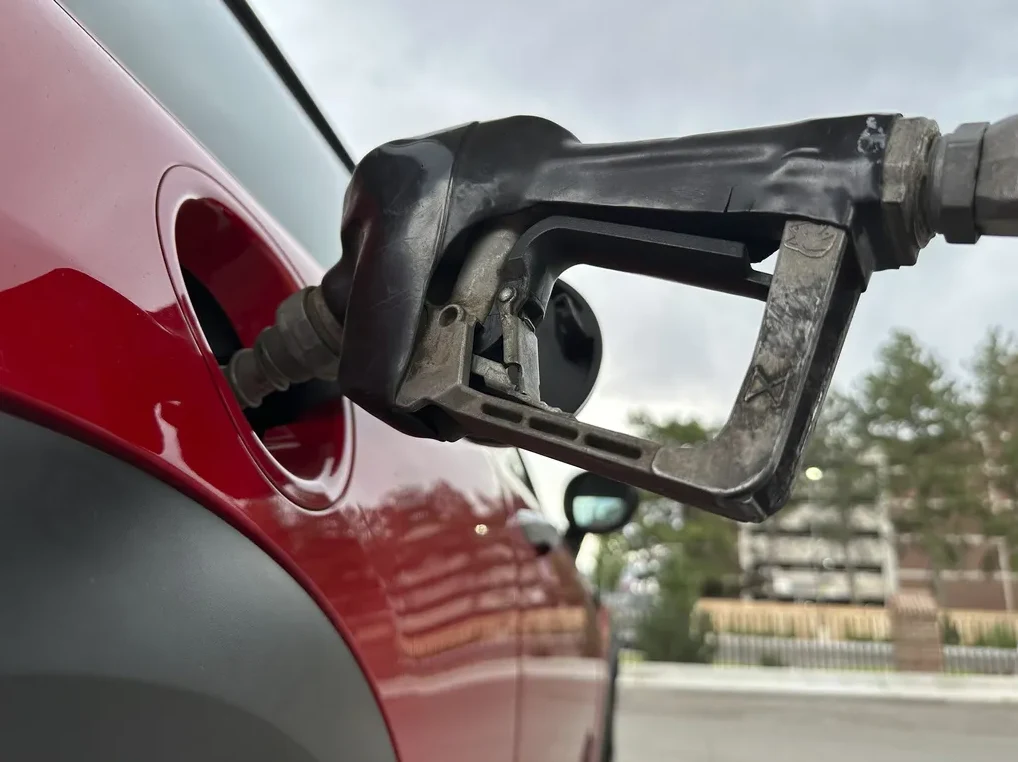 Pištolj za sipanje goriva koji ulazi u rezervoar crvenog automobila.