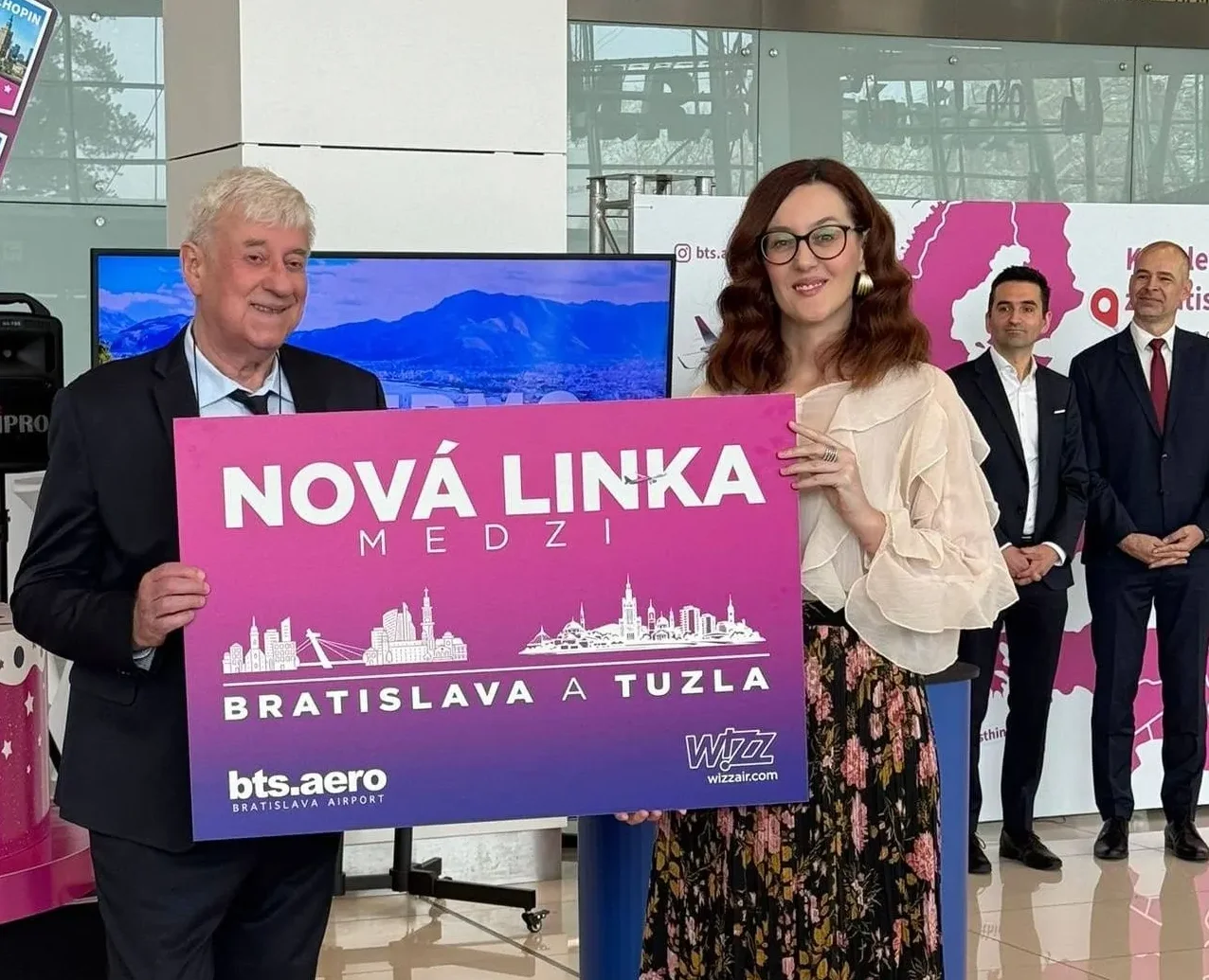Dvoje ljudi drži natpis na kojem piše "Nova linija medju Bratislavu a Tuzla" uz logotipe Bratislava Airport i Wizz Air.