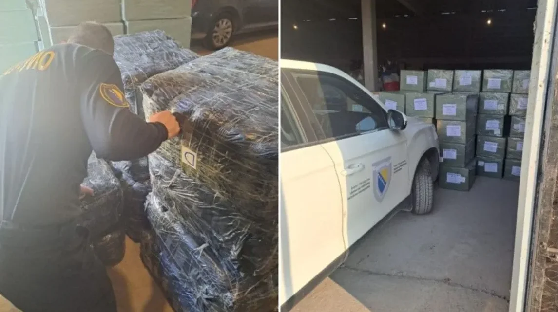 Službenik u uniformi sa oznakama Bosne i Hercegovine pregleda velike, plastificirane pakete u magacinu. Pored paketa parkirano je službeno bijelo vozilo sa grbom i natpisima Bosne i Hercegovine. U pozadini su vidljiva još skladištena dobra.