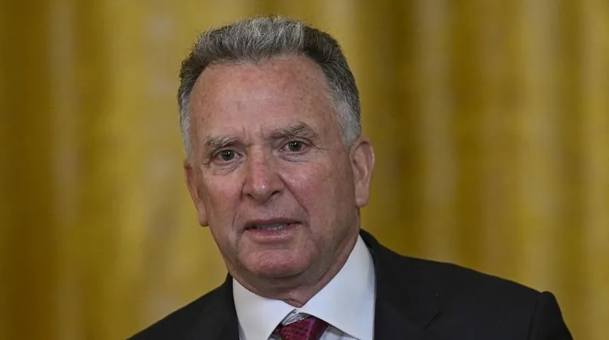 Portret starijeg muškarca sijede kose obučenog u tamno odijelo i crvenu kravatu.