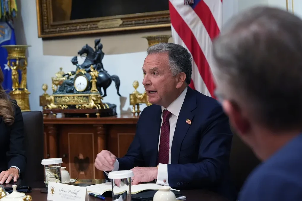 Steve Witkoff sjedi za stolom s bilježnicom, govoreći sa podignutom rukom.