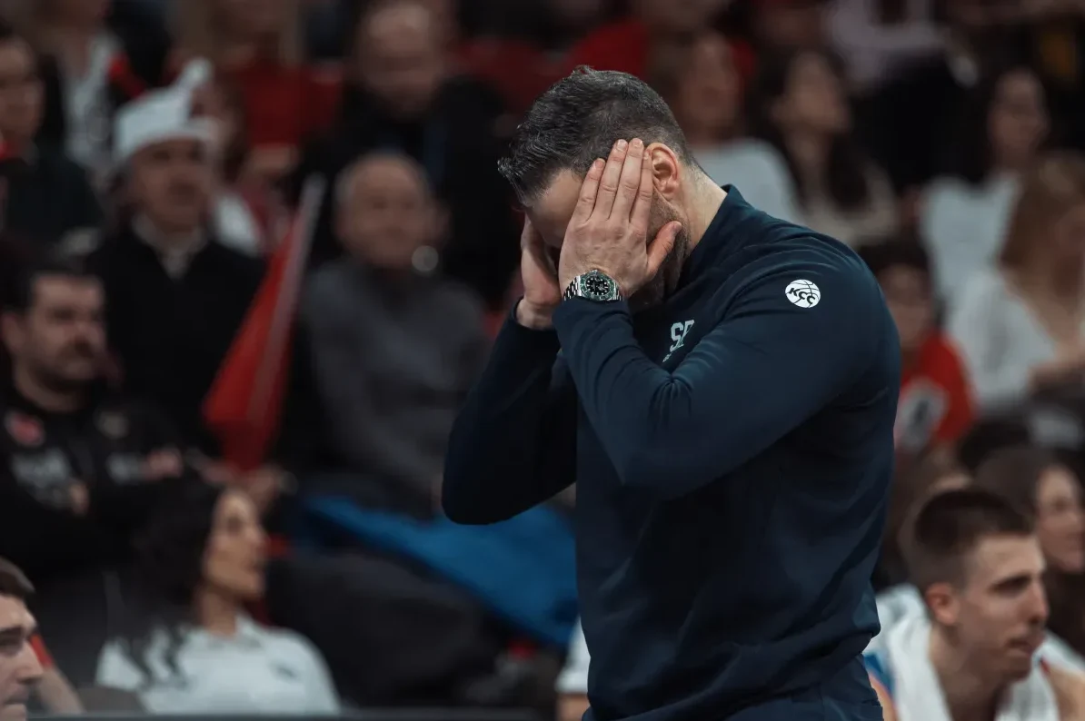 Trener košarkaša pokriva uši rukama, izražavajući razočarenje ili frustraciju.