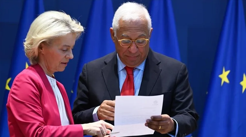 Ursula von der Leyen i Antonio Costa gledaju u dokument ispred zastave Evropske unije.