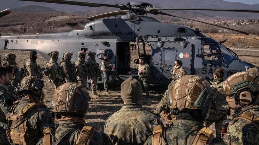 Vojnici u punoj opremi okupljeni oko vojnog helikoptera tokom vježbe.