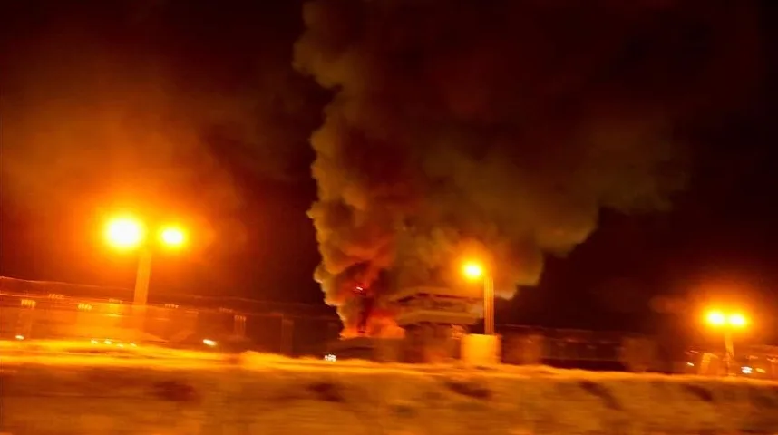 Veliki stub dima i vatre iznad zapaljene građevine noću, osvijetljen sa više uličnih lampi.