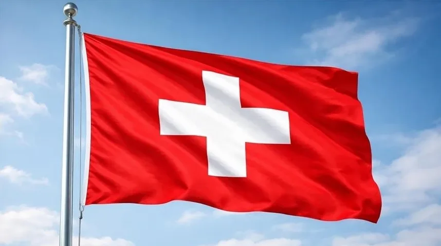 Zastava Švicarske sa bijelim krstom na crvenoj pozadini, na jarbolu, na plavom nebu sa oblacima.