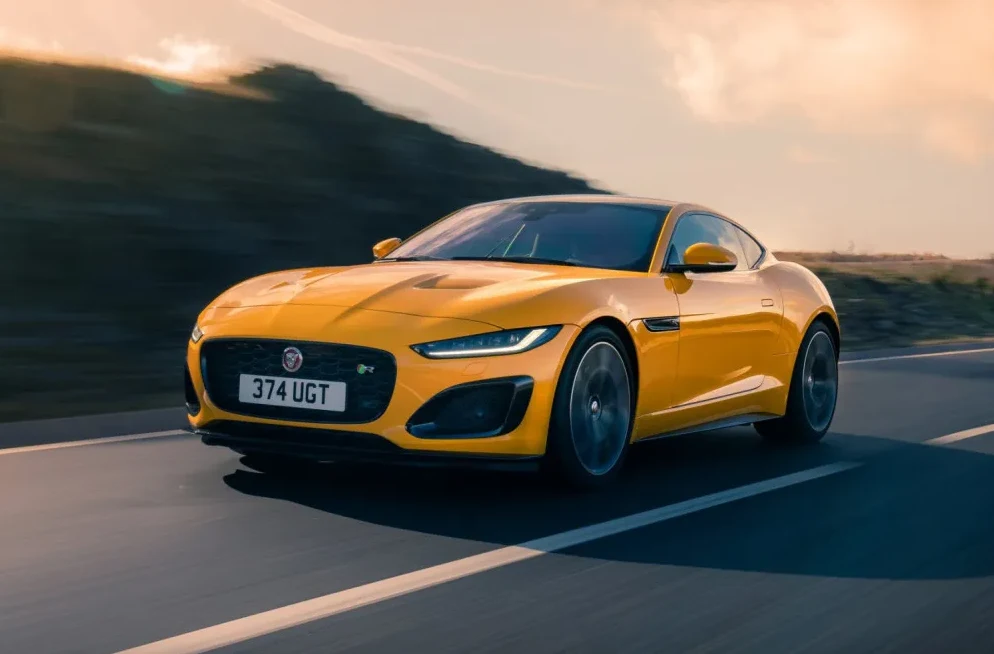 Žuti sportski automobil Jaguar F-Type vozi se cestom pri zalasku sunca.