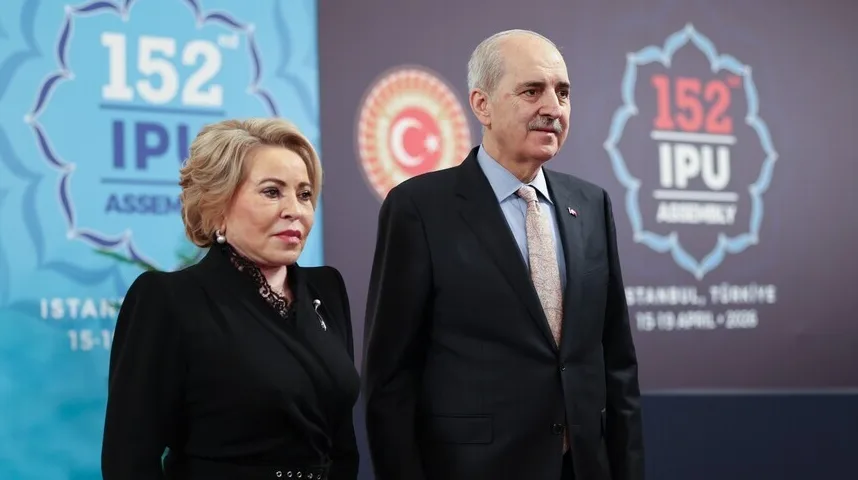 Gospoda i dama u svečanim odijelima ispred postera 152. Skupštine IPU-a u Istanbulu.