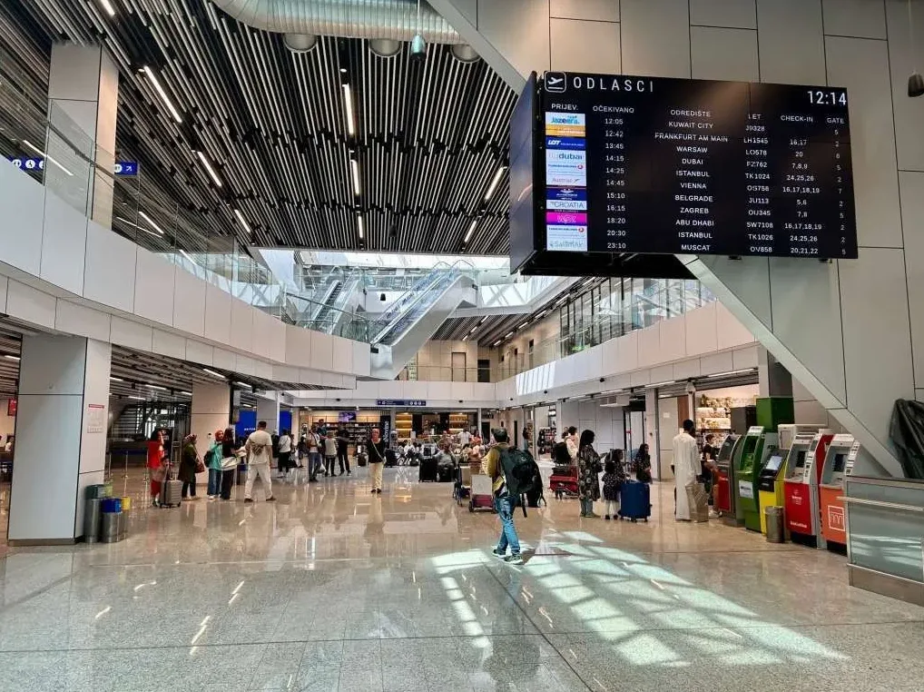 Veliki displej sa informacijama o odlascima letova na aerodromu, prikazuje vrijeme 12:14.