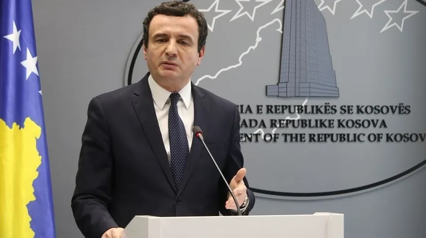 Političar Albin Kurti u tamnom odijelu i bijeloj košulji sa plavom kravatom, govori za govornicom.