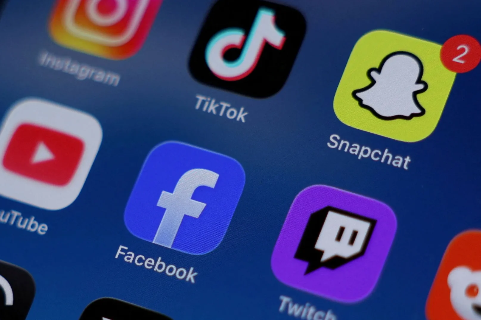 Ikone popularnih aplikacija društvenih medija kao što su Instagram, TikTok, Snapchat, YouTube, Facebook i Twitch prikazane na tamnoplavom ekranu telefona.