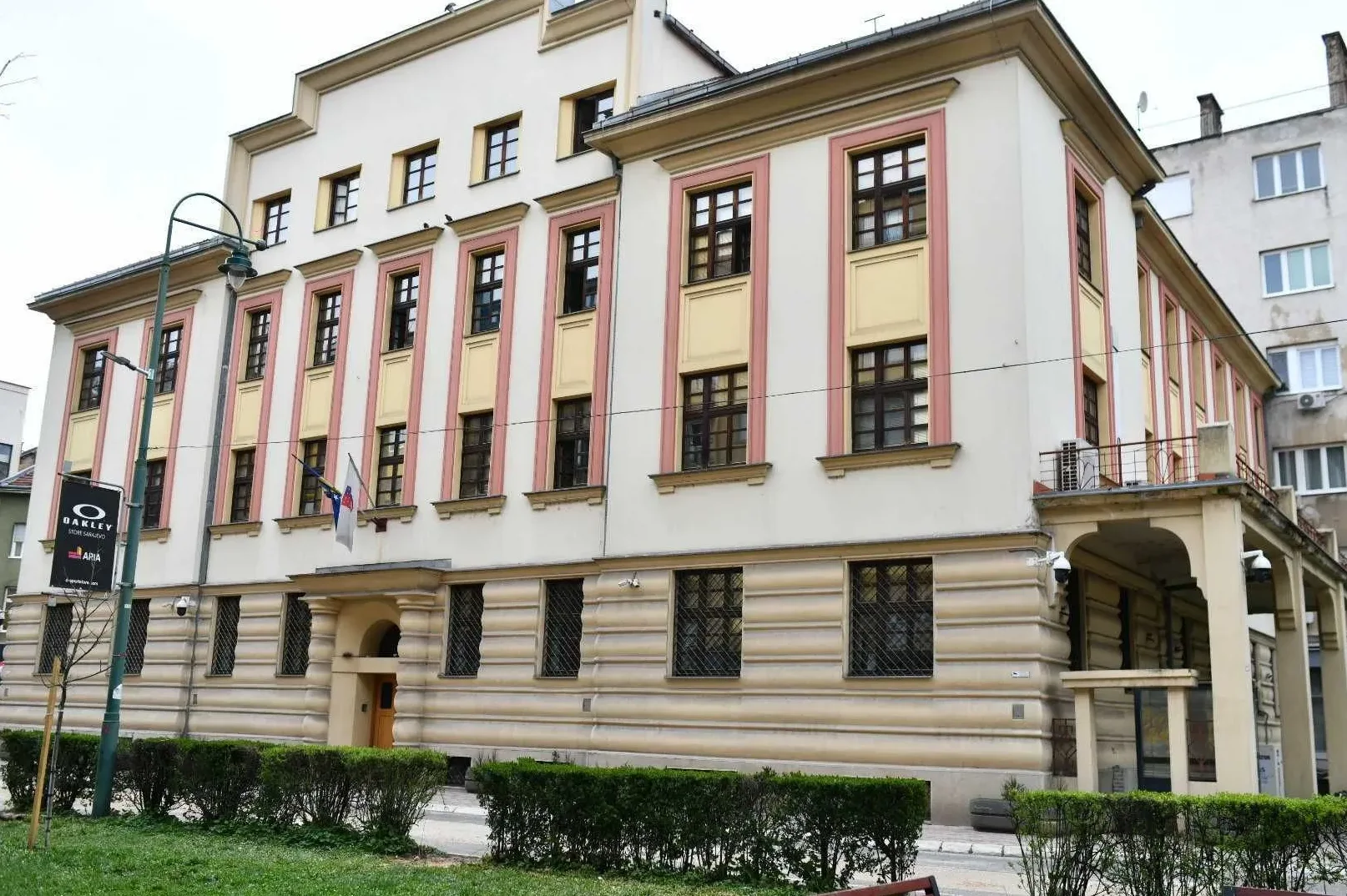 Fasada svijetlo krem boje sa žutim i ružičastim ukrasnim trakama, te tamnim prozorima.